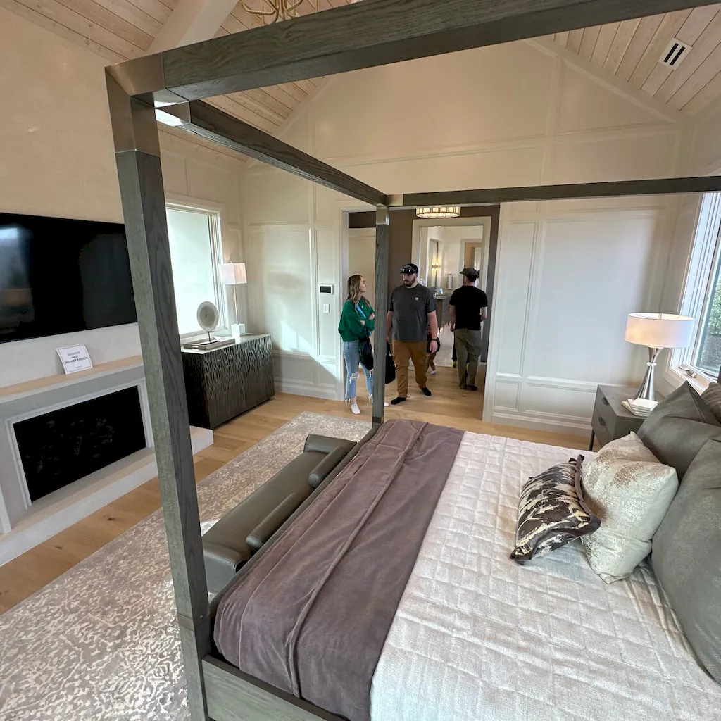 Flooring professionals speaking with a homeowner customer on light hardwood in a vaulted master bedroom walkthrough.