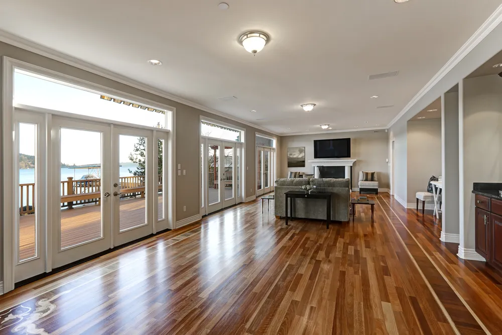 Living room with polished hardwood floors, decorative wood inlay border, medallion corner, and lake view doors.