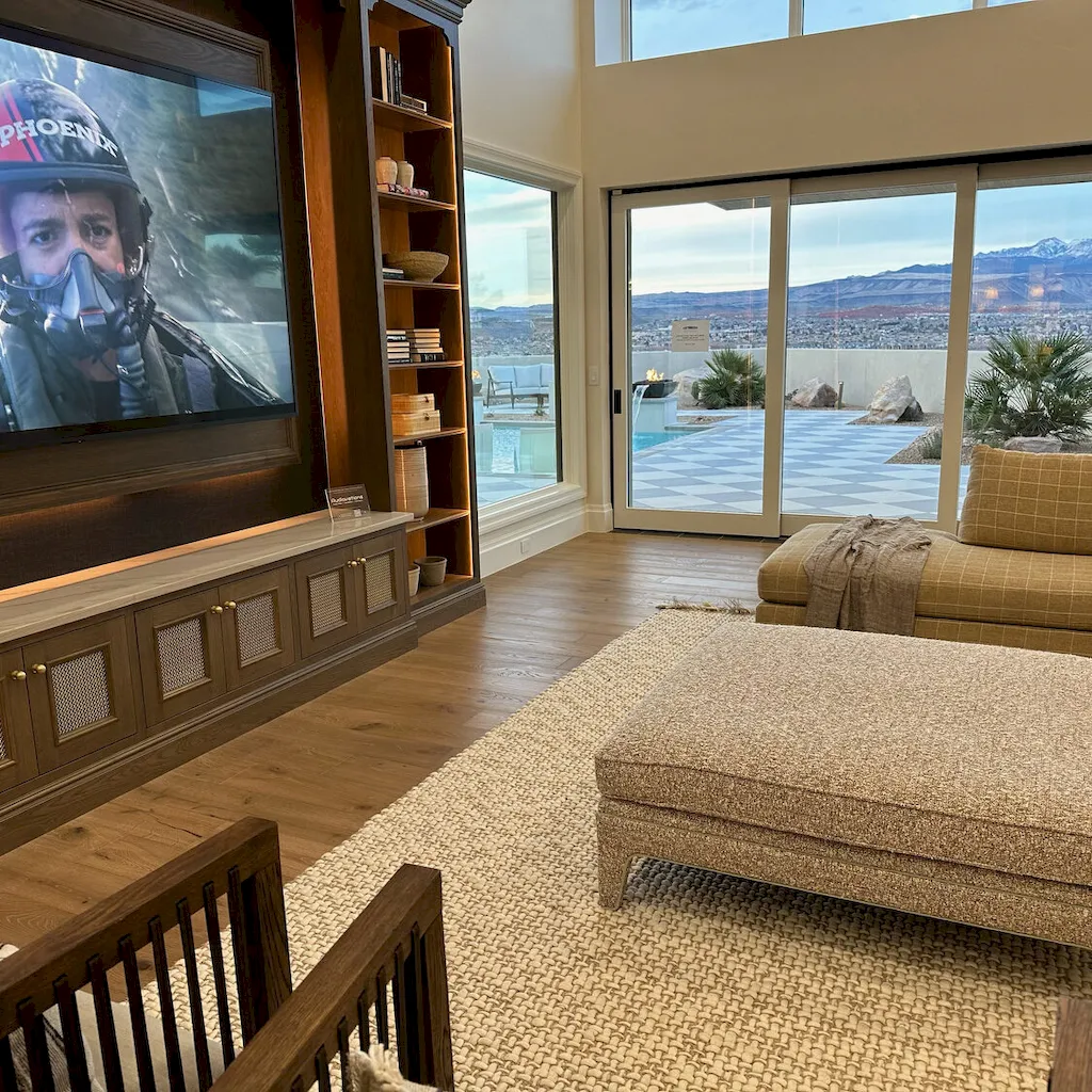 Luxury living room with wide-plank light oak hardwood, built-in entertainment center, and red rock mountain patio view.