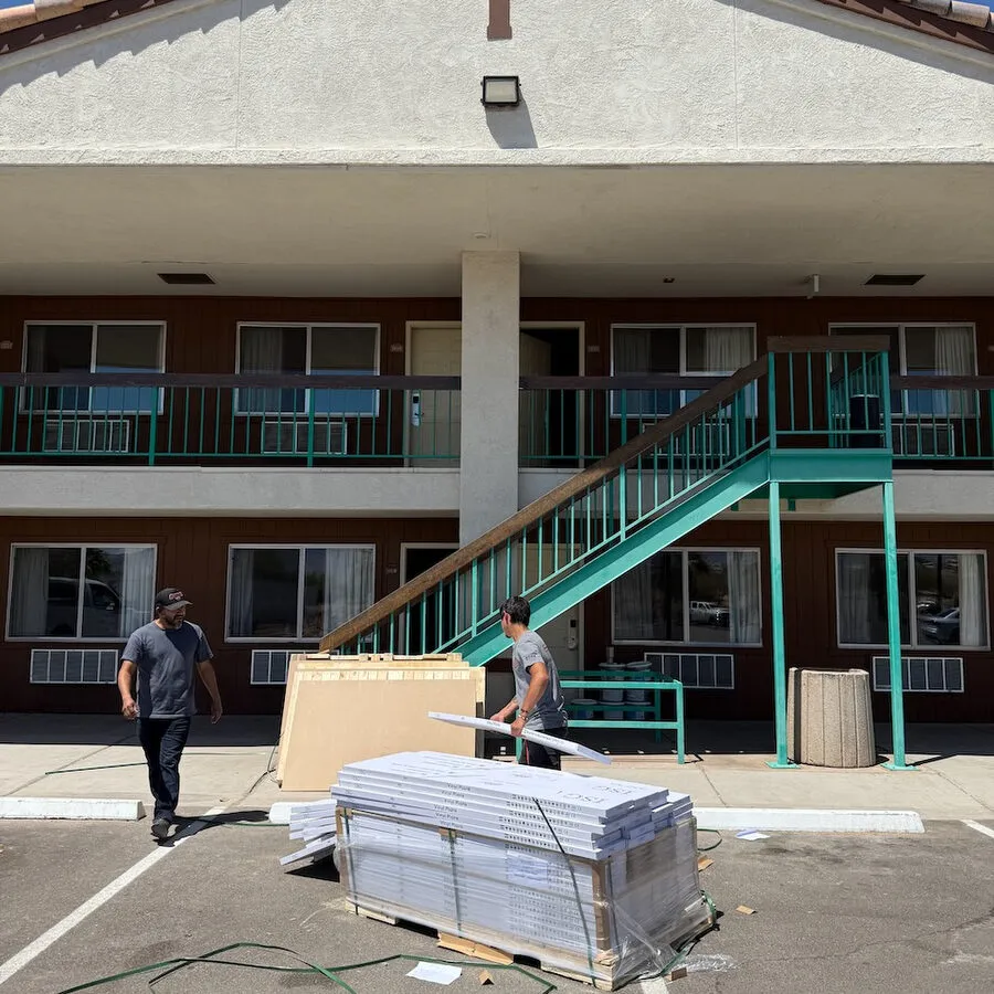 Red Rock Flooring workers unloading a pallet of vinyl plank flooring at a two-story motel renovation project.